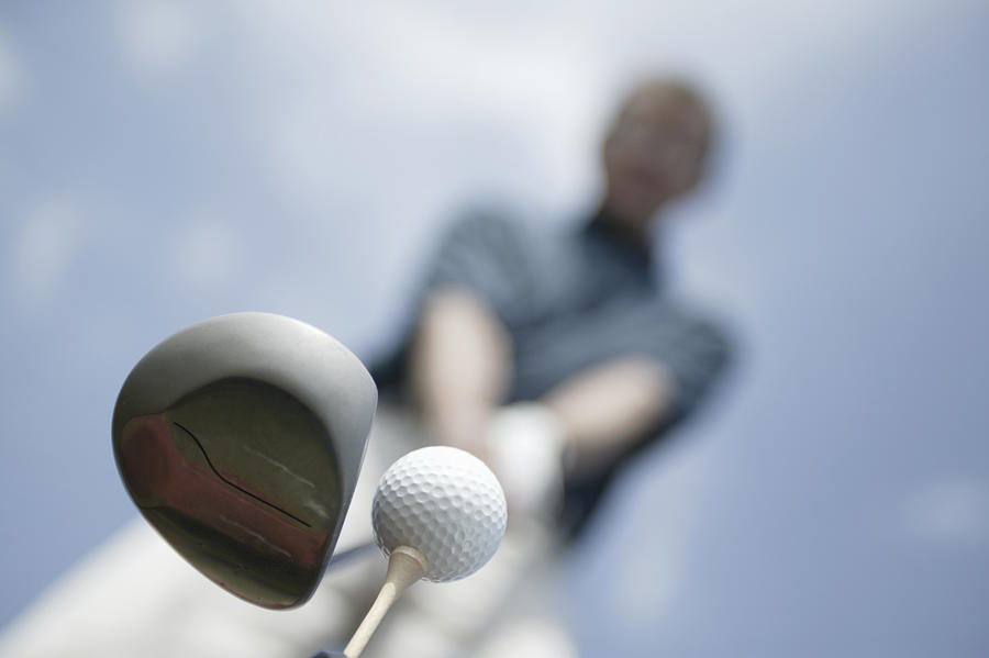 Man preparing to hit golf ball Photograph by Comstock