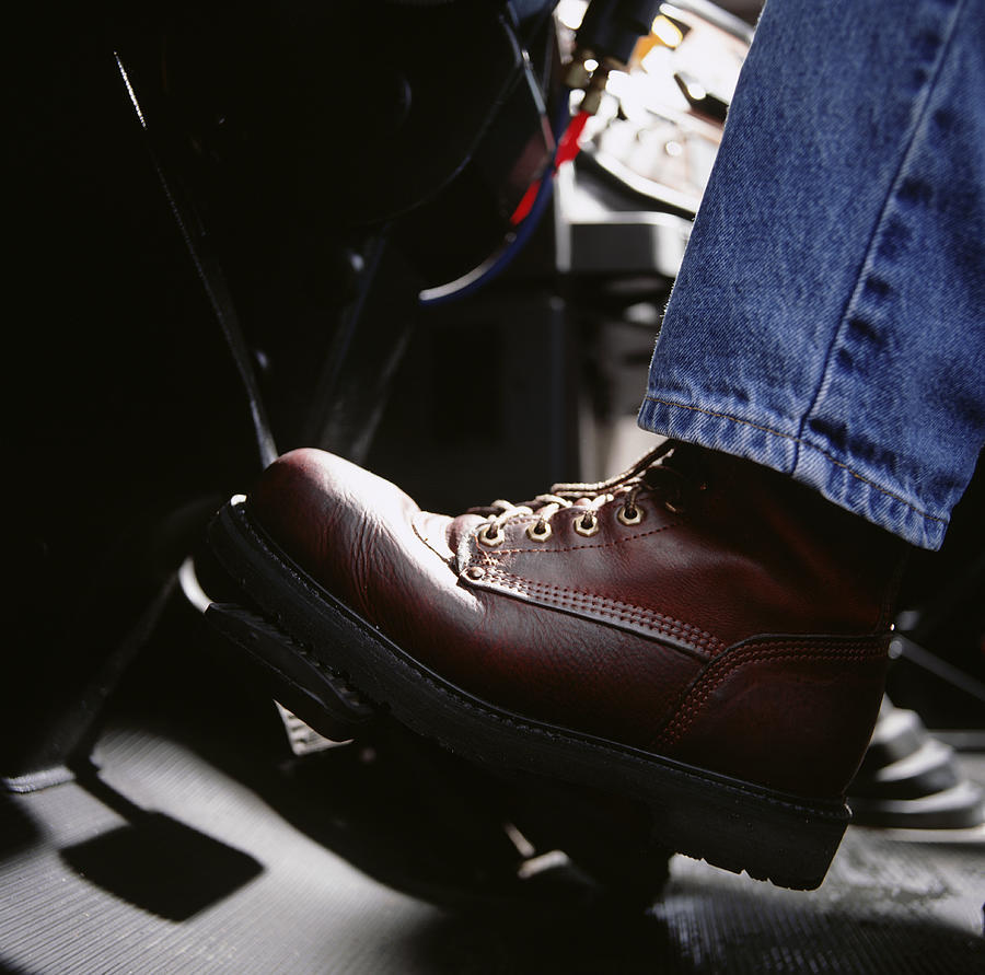 Man pressing car pedal, close-up, low section Photograph by Ryan McVay