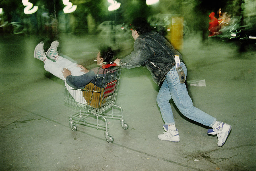 Man pushing man in shopping cart, blurred motion Photograph by Christopher Pillitz