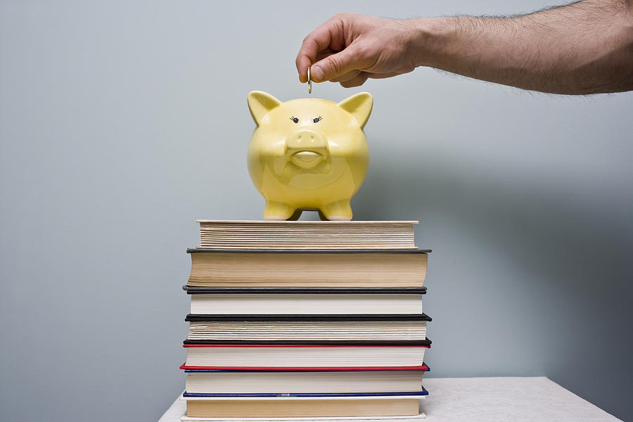 Man puts coin in piggy bank Saving Money for School Photograph by Michellegibson