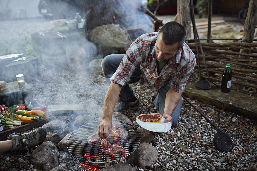 Man putting meat on homemade grill Photograph by Klaus Vedfelt