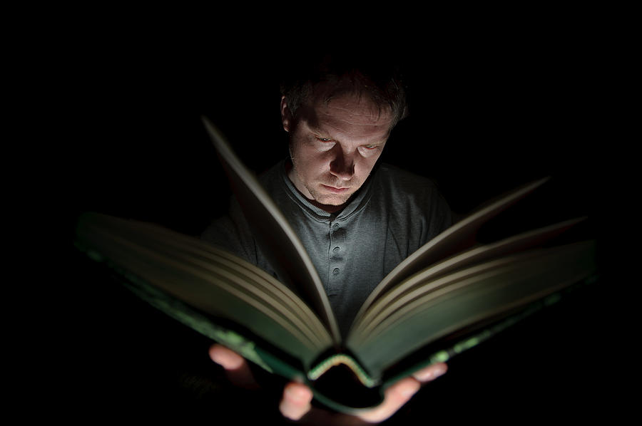 Man Reading Book Illuminated by Light Photograph by Nuzulu