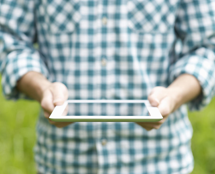 Man reading from a digital tablet in a field Photograph by Dougal Waters