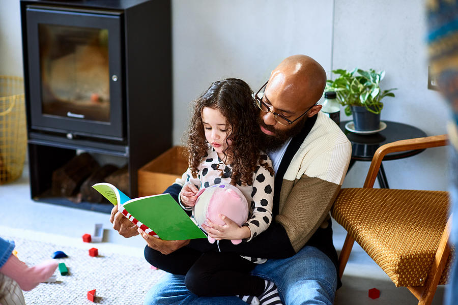 Man reading story book with daughter Photograph by 10000 Hours