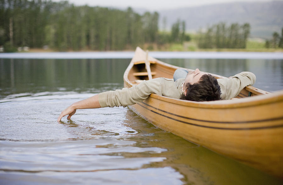 Man reclining in canoe on lake Photograph by Sam Edwards