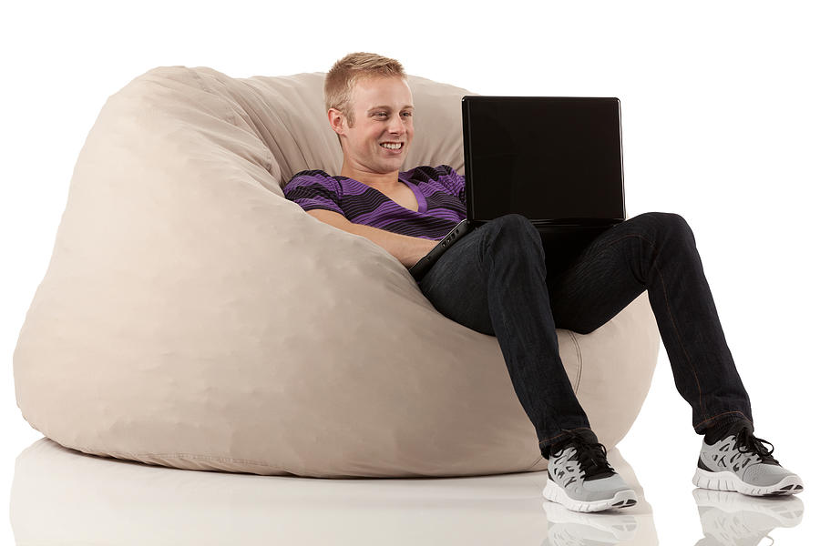 Man reclining on bean bag and using a laptop Photograph by 4x6
