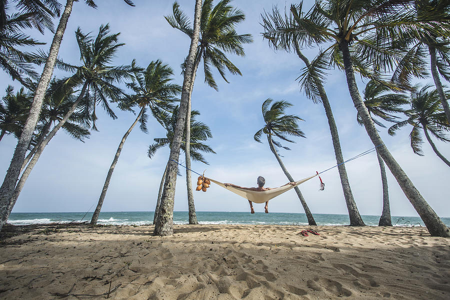 Man relaxing in hammock in tropical location. Photograph by David Trood
