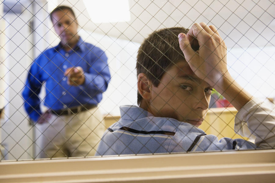 Man Reprimanding Boy Behind Fence Photograph by Fuse