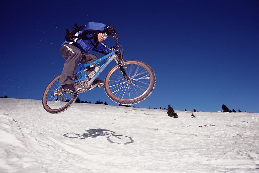Man riding mountain bike on snow Photograph by Image Source