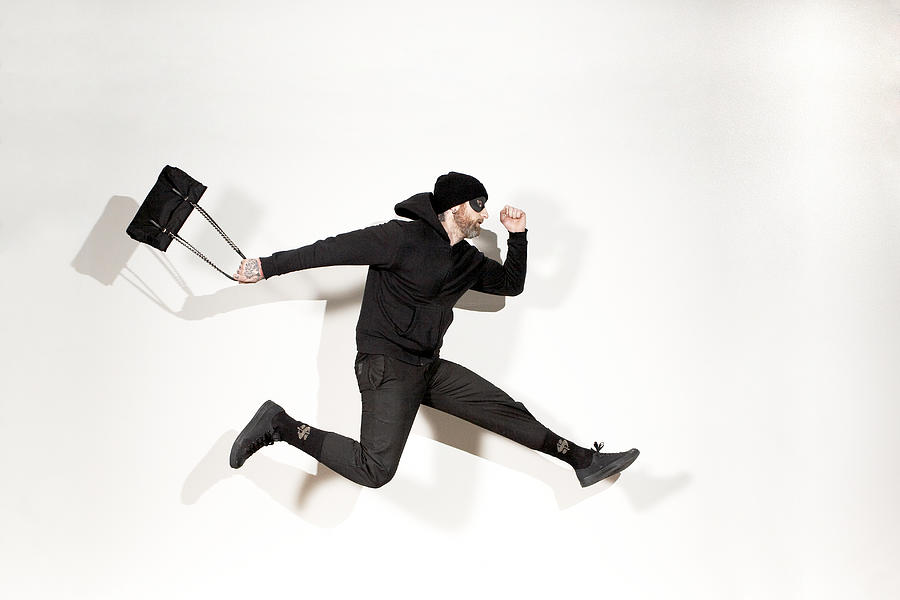 Man running mid-air with handbag, side view Photograph by Ballyscanlon