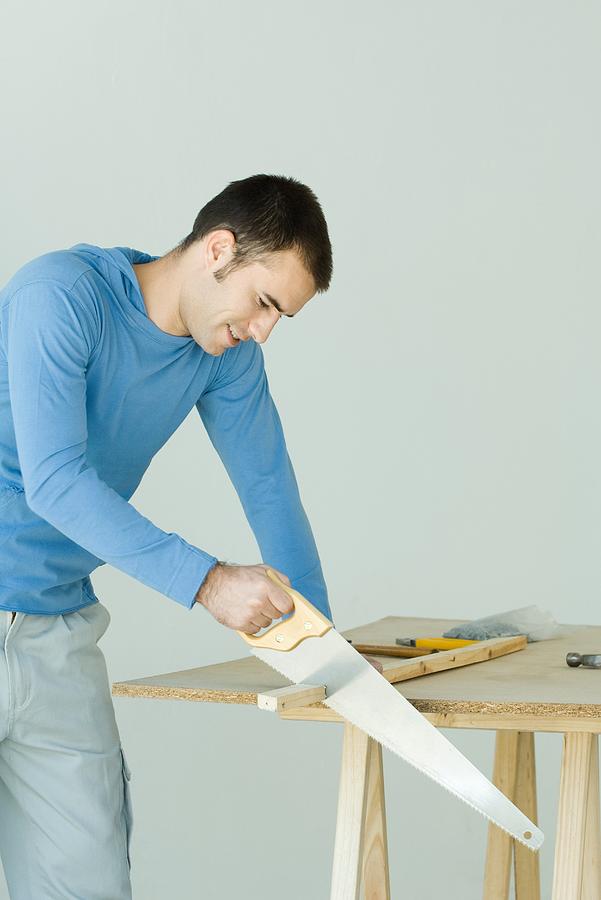Man sawing wood plank Photograph by PhotoAlto/Odilon Dimier
