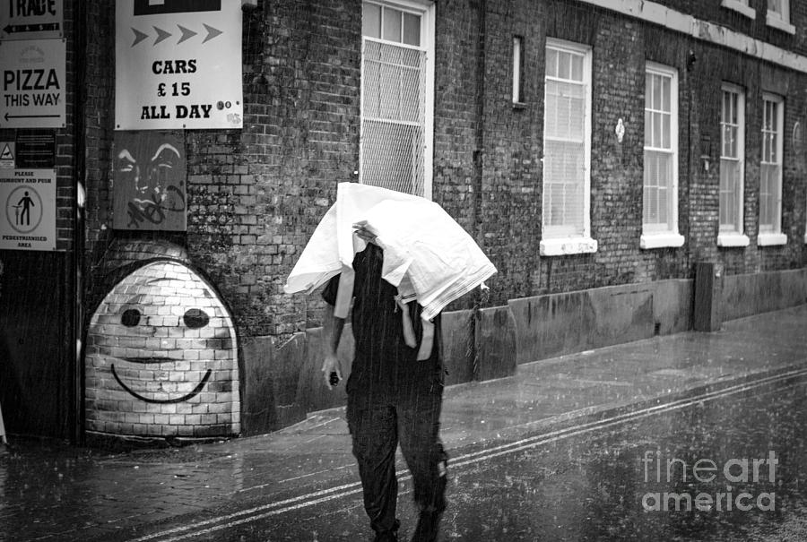 Man seeks to keep his head  out of the wet rain. Photograph by Cyril Jayant