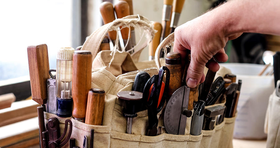 Man selecting a hand tool from a bag on workbench Photograph by Gary John Norman