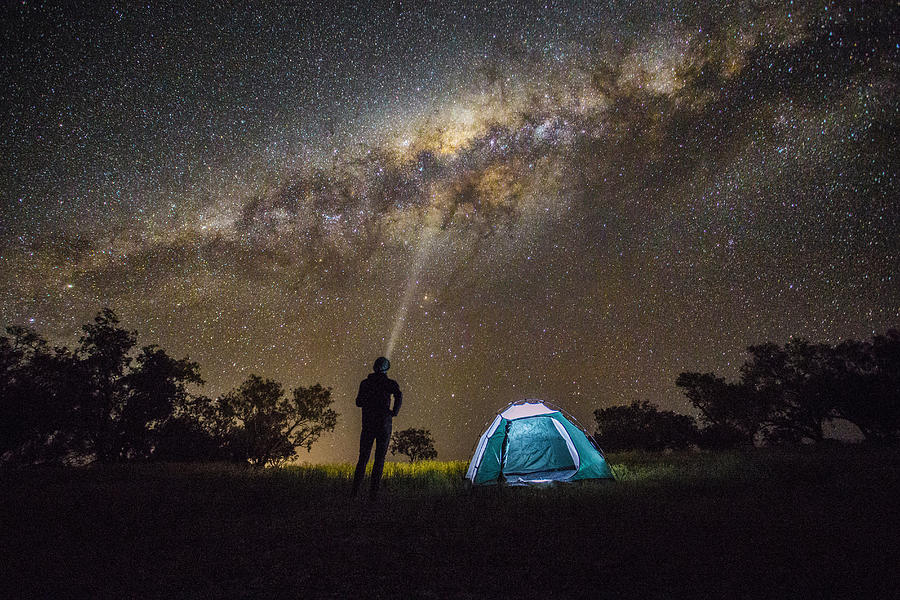 Man shining a light into the Milky Way. Photograph by David Trood