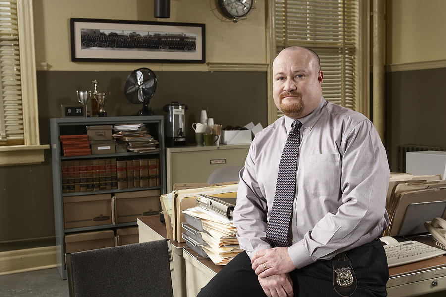 Man sitting on desk in office, portrait Photograph by Darrin Klimek