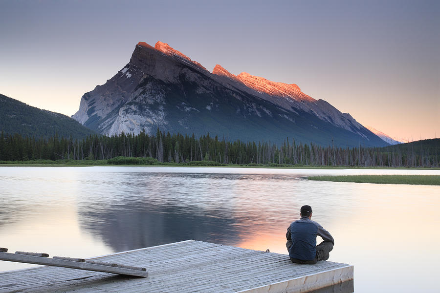 Man sitting on edge of dock by Mount Rundle, Banff Photograph by Veni