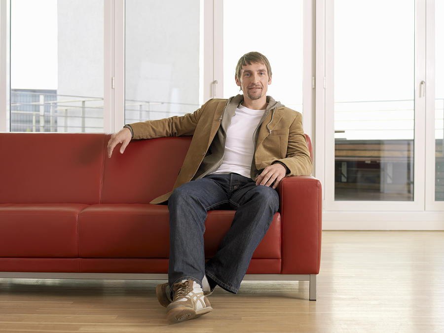 Man sitting on sofa, portrait Photograph by Rayman