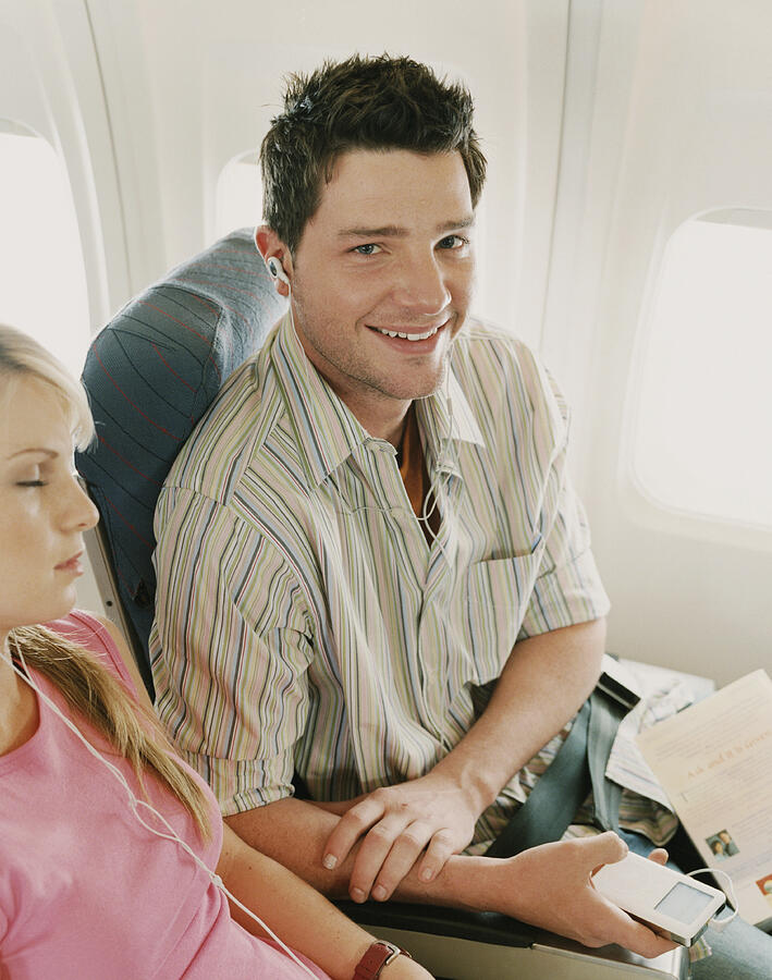 Man Sitting with a Woman on a Plane Photograph by Digital Vision.