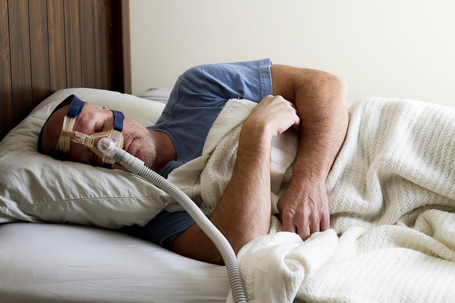 Man Sleeping in Bed with Sleep Apnea Mask Photograph by Nicolesy