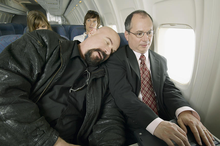 Man Sleeping on a Plane With His Head Resting on a Businessmans Shoulder Photograph by Digital Vision.