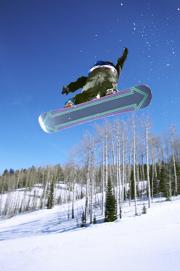 Man snowboarding, jumping in mid-air, upward view Photograph by John P Kelly