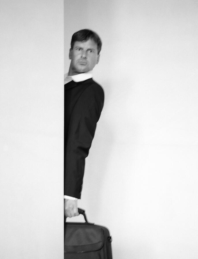 Man standing behind a wall, holding a bag, blurred b&w Photograph by Matthieu Spohn