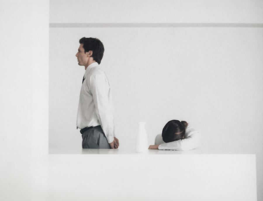 Man standing behind table, side view, woman with head down on arm Photograph by Matthieu Spohn