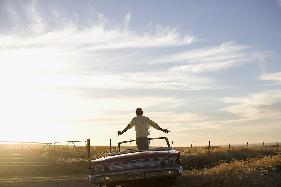 Man standing in convertible in countryside Photograph by J.A. Bracchi