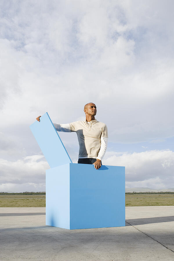 Man standing in large blue open box Photograph by Martin Barraud
