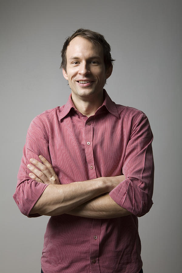 Man standing with arms crossed, smiling, portrait Photograph by Allison Michael Orenstein