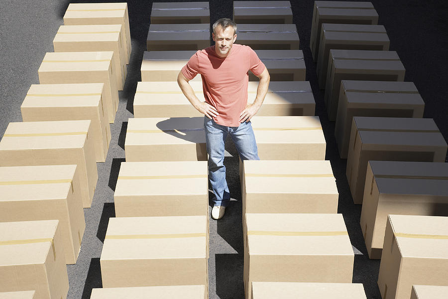 Man standing with lines of boxes in roadway Photograph by Martin Barraud
