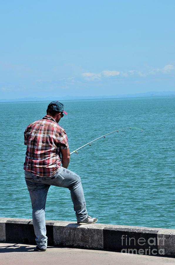Man stands by Black sea shore with fishing pole Batumi Georgia