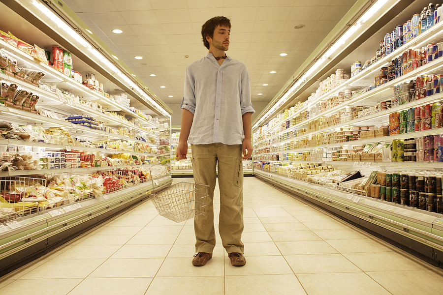 Man stood in supermarket Photograph by Peter Cade