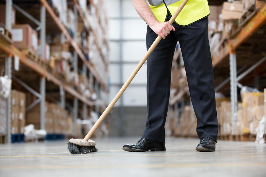 Man sweeping warehouse floor with broom Photograph by Image Source