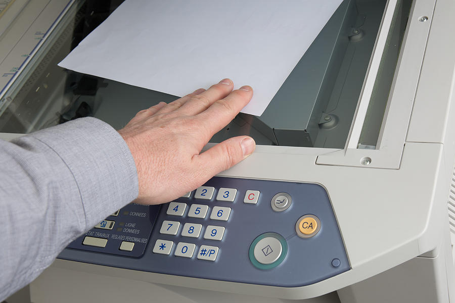 Man takes out  documents from printer or photocopier Photograph by OceanProd
