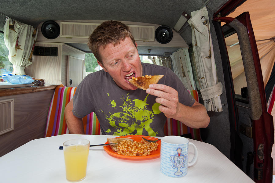 Man tucks into breakfast in camper van Photograph by Paul Mansfield Photography