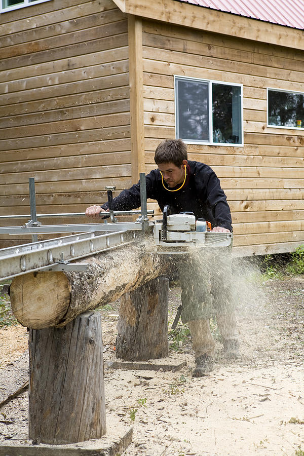 Man using chainsaw lumber maker, McCarthy, Alaska. Photograph by Aurora Open