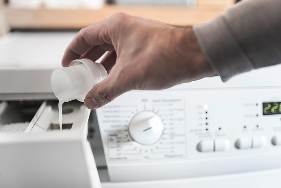 Man Using Dosing Aid To Fill Fabric Softener Into Washing Machine Photograph by Christian Horz