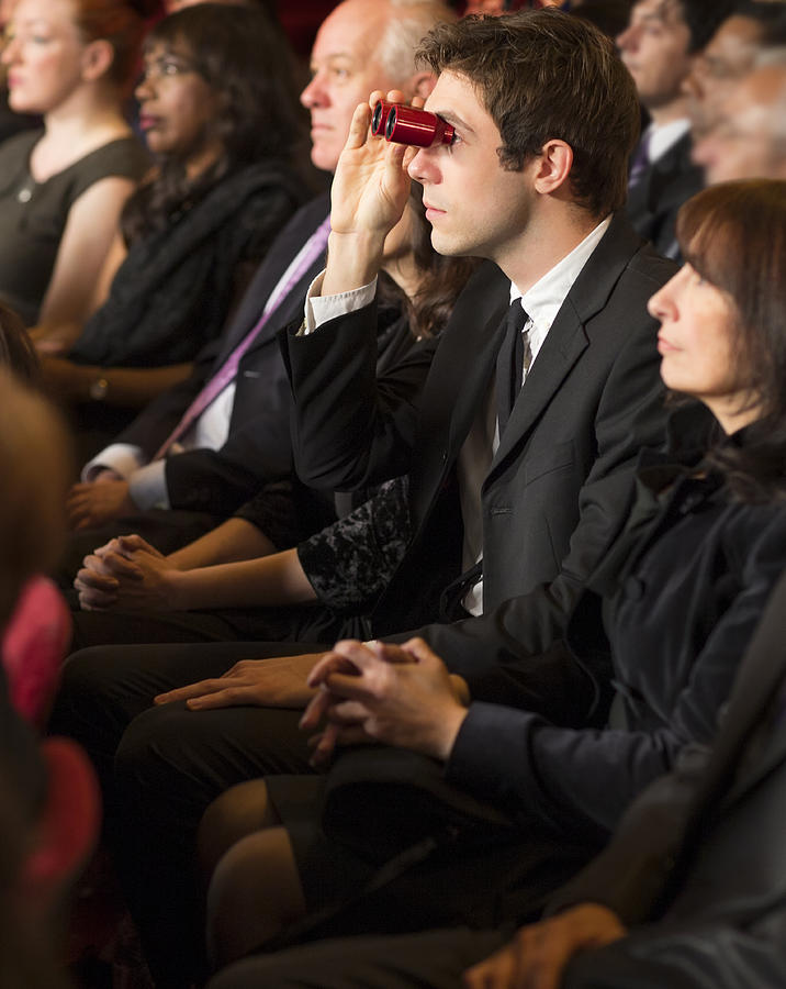 Man using opera glasses in theater audience Photograph by Caiaimage/Robert Daly