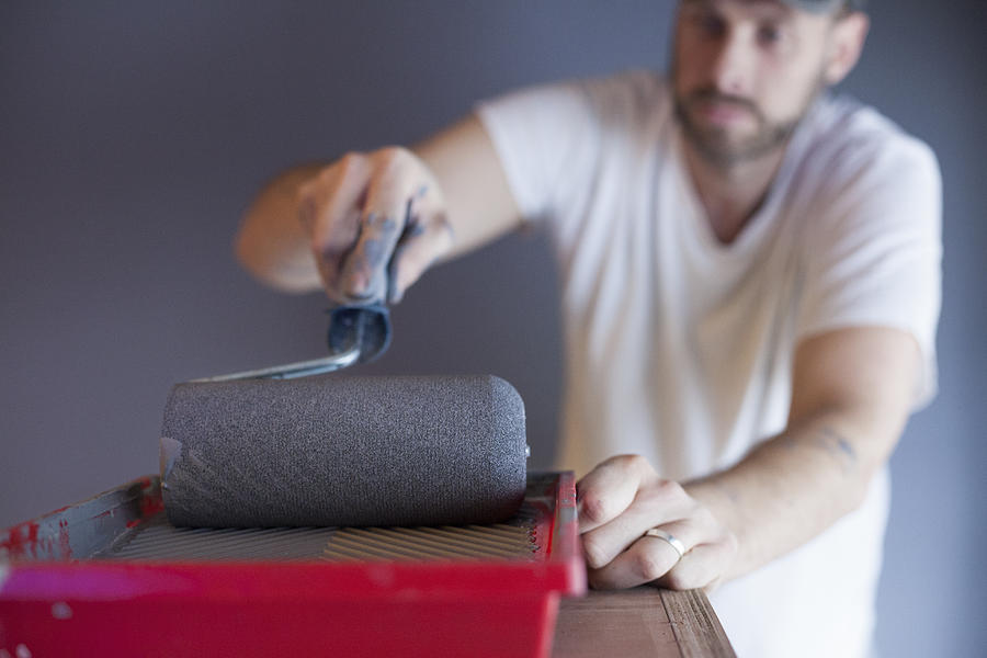 Man using paint roller to paint the walls with gray color Photograph by Kathrin Ziegler