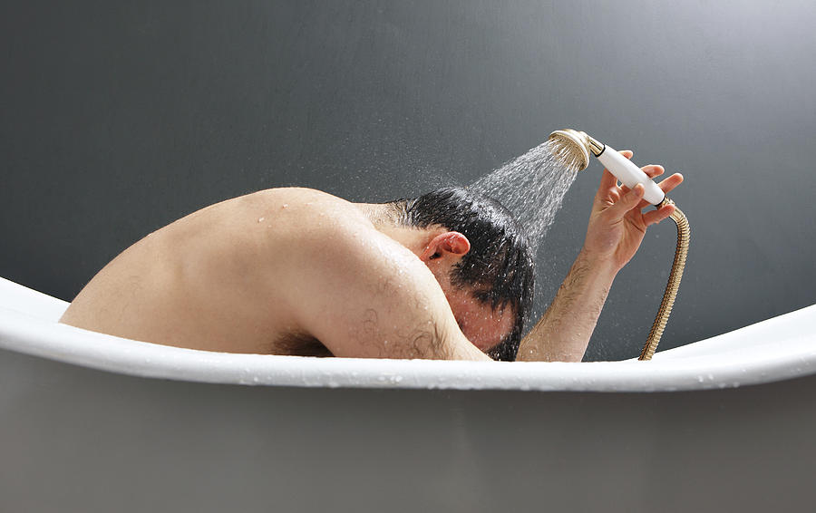 Man Using Shower In Bath Tub Photograph by John Slater