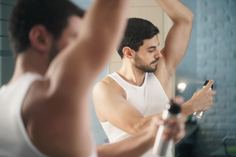 Man Using Spray Deodorant On Underarm For Bad Smell Photograph by Diego_cervo
