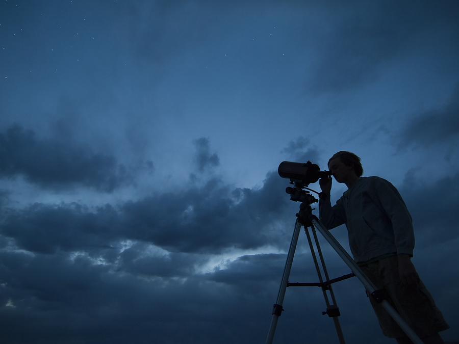 Man using telescope on tripod Photograph by Erik Isakson