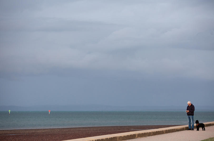 Man walking dog on pathway near seaside Photograph by Marianne Purdie