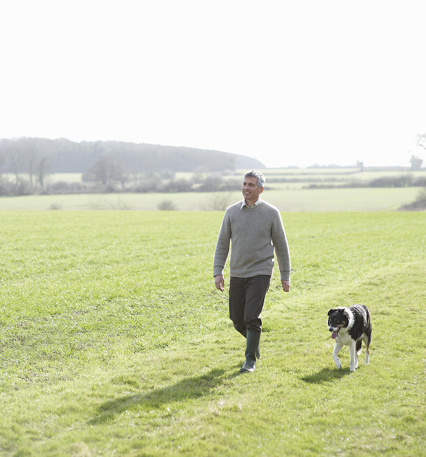 Man walking in countryside with pet dog Photograph by Dougal Waters