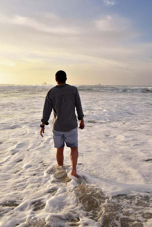 Man walking into the ocean at sunset stock photo Photograph by Mark Stout