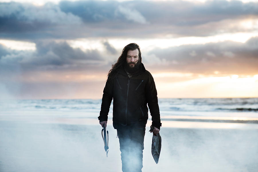 Man walking on beach with speargun and fish Photograph by Robin Skjoldborg