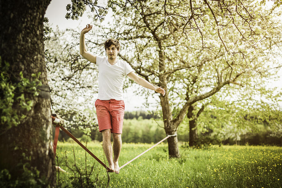 Man walking on tightrope in field Photograph by Manuel Sulzer