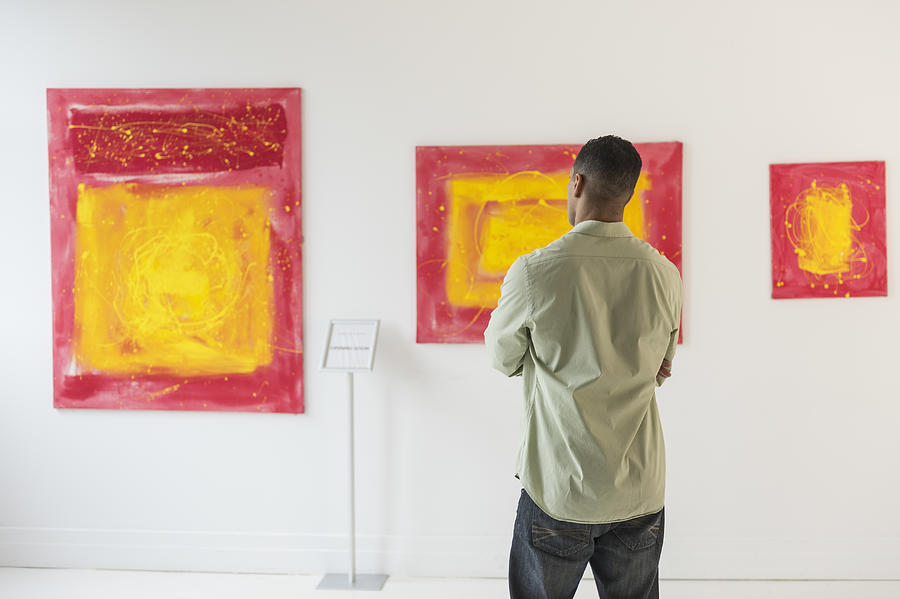 Man watching paintings in modern art gallery Photograph by Tetra Images