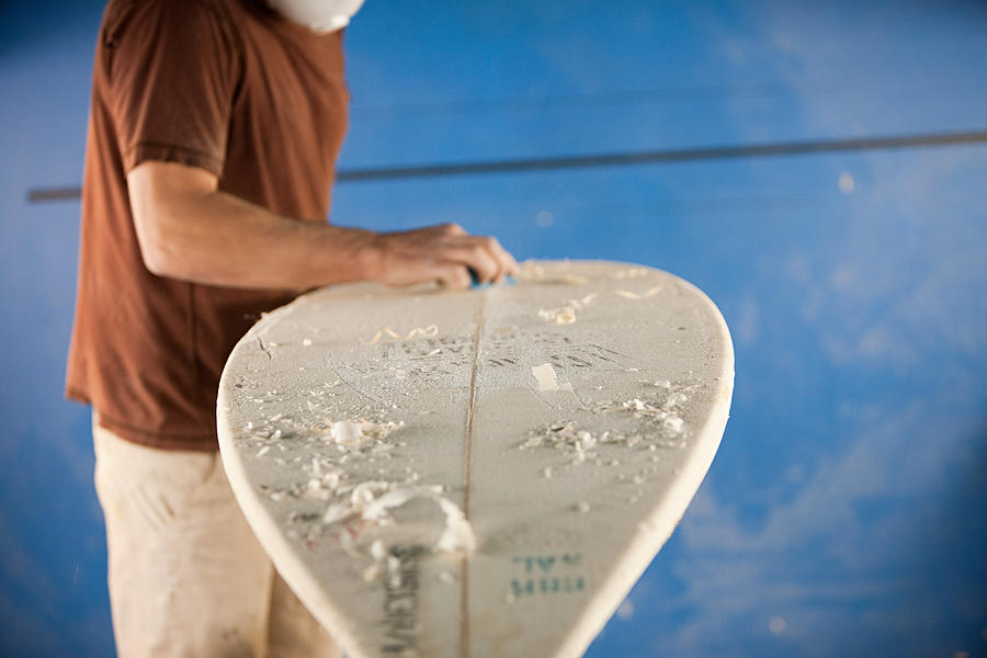 Man waxing surfboard Photograph by Image Source